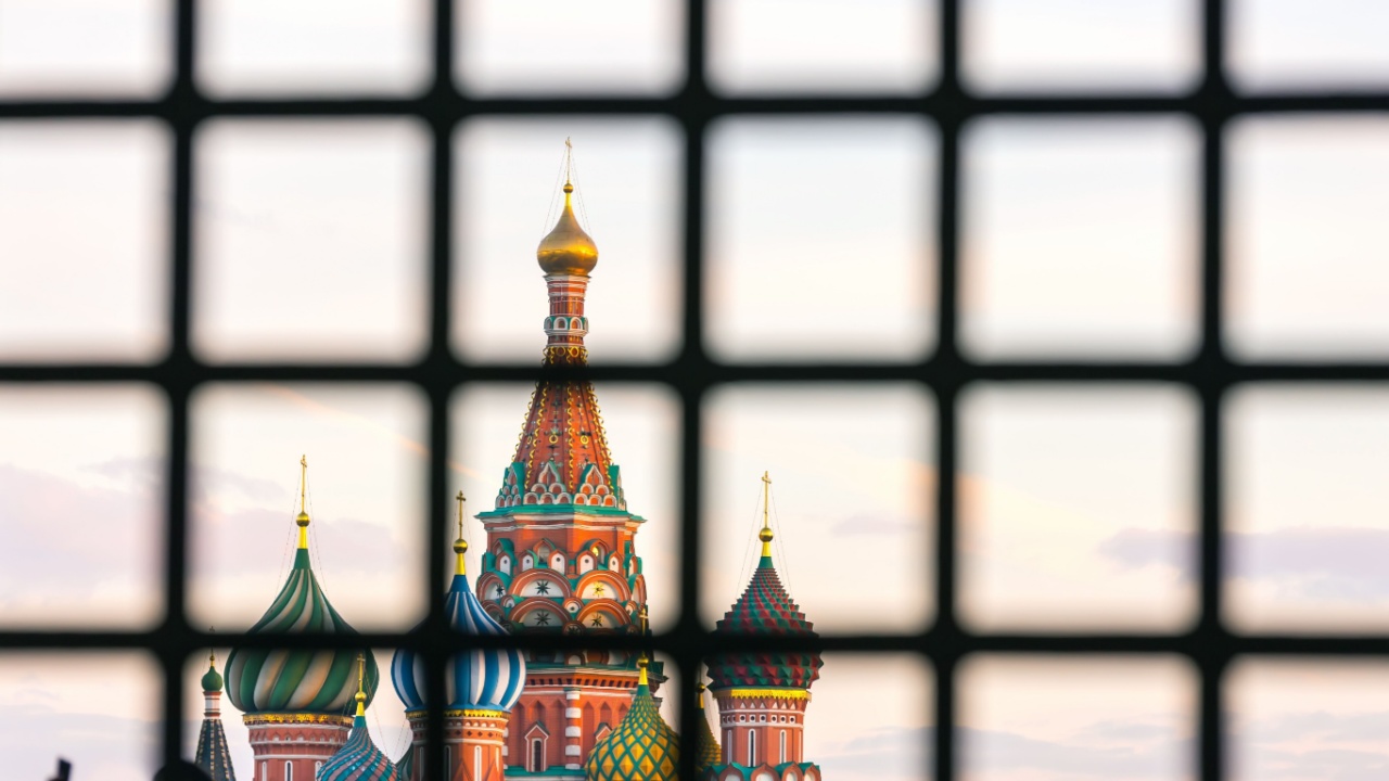 St. Basil's Cathedral on Red Square with a large number of people is hidden behind bars. Moscow behind bars, Russia.